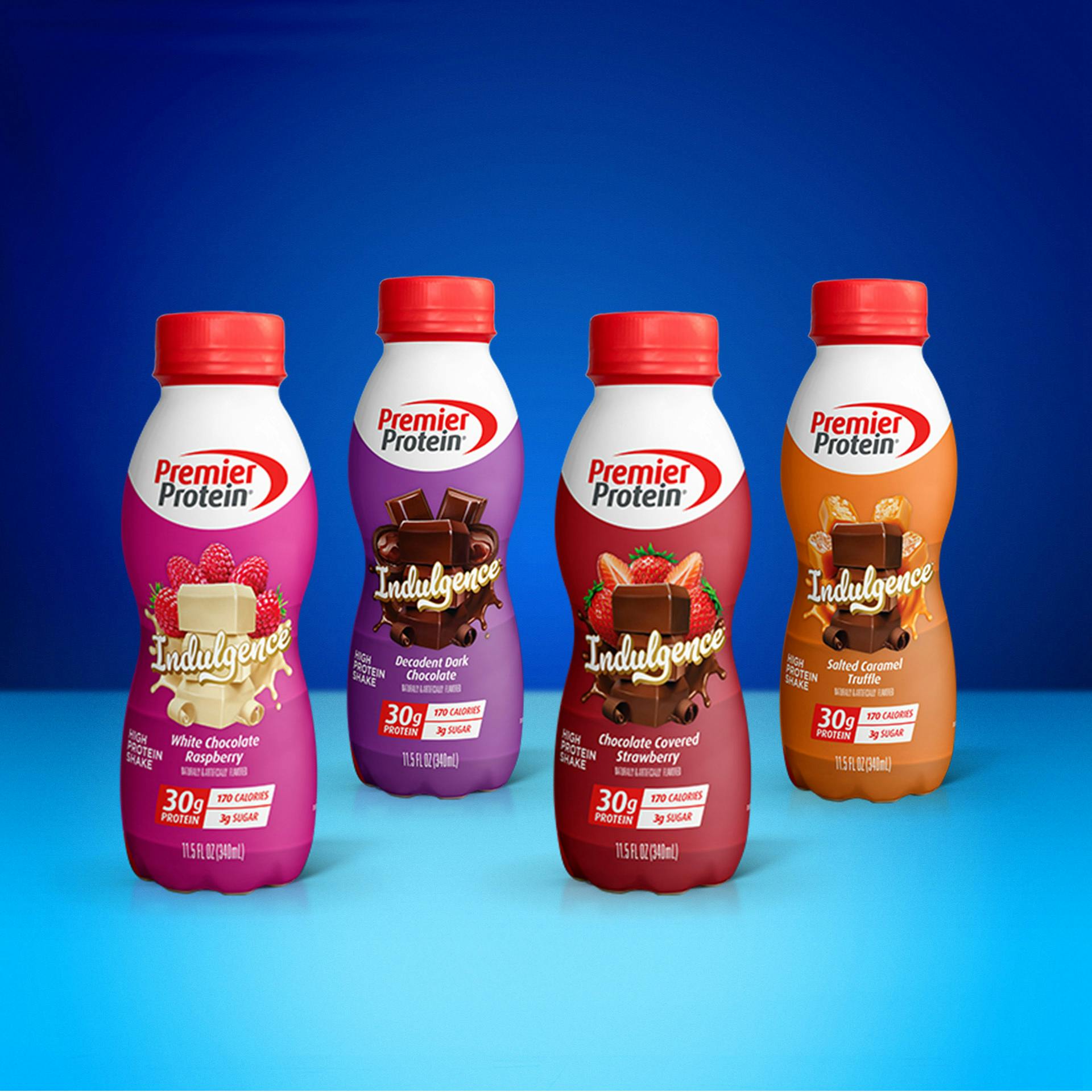 Four Premier Protein Indulgence bottles sitting against a blue background.